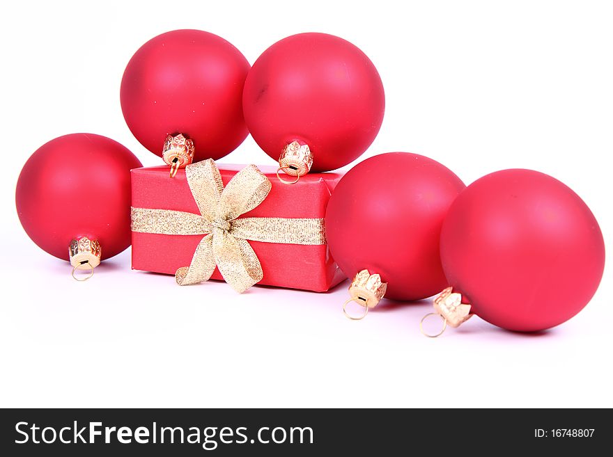 Red matte christmas balls and a gift in red wrapping on white background, with space for your text