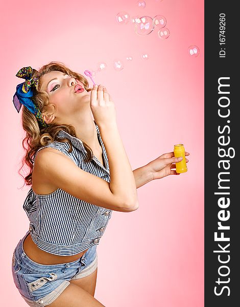 Beauty girl blows bubbles against a pink background. Beauty girl blows bubbles against a pink background