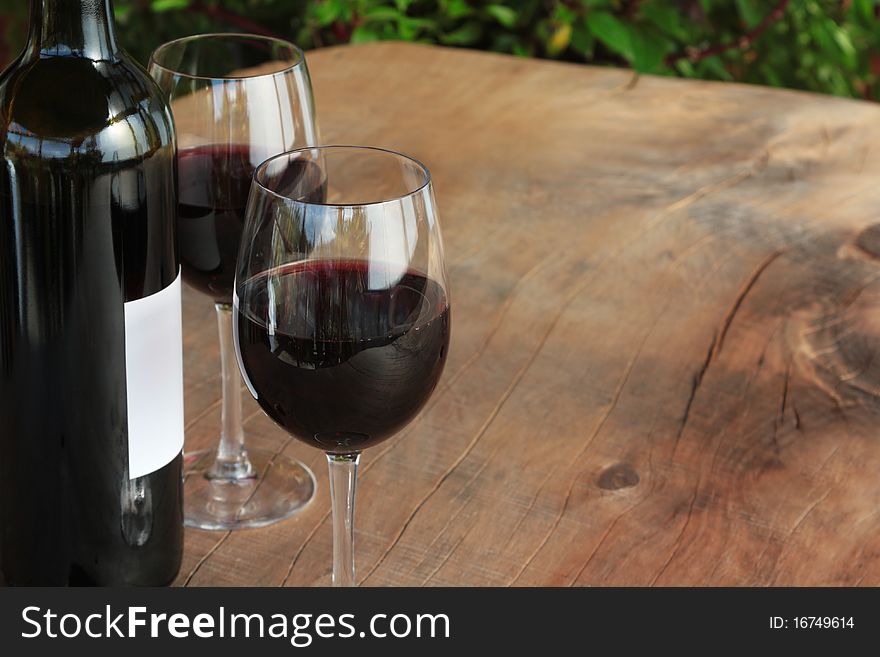 Bottle & glasses of red wine on an outdoor wooden table (see more…). Bottle & glasses of red wine on an outdoor wooden table (see more…)