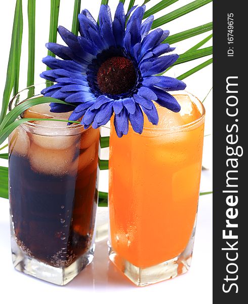 Orange and cola drink glasses with gerbera flower isolated on white background. Orange and cola drink glasses with gerbera flower isolated on white background.