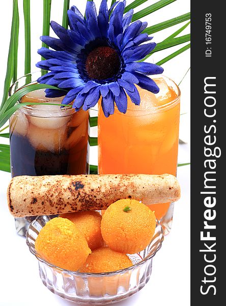 Orange and cola drink glasses with indian sweets isolated on white background. Orange and cola drink glasses with indian sweets isolated on white background.