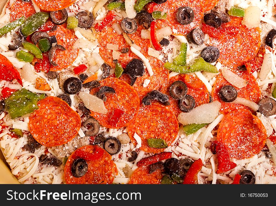 Raw pizza with pepperoni, bell peppers, black olives and onions. Raw pizza with pepperoni, bell peppers, black olives and onions