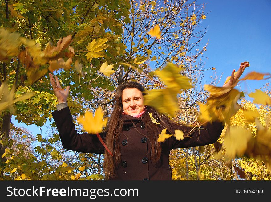 A girl under falling leaves in autumn scenery. A girl under falling leaves in autumn scenery