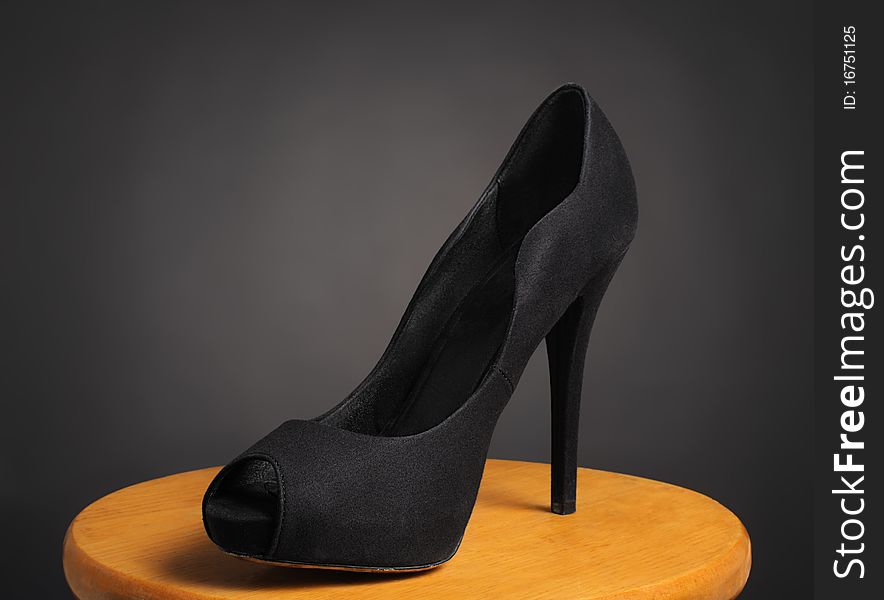 A stiletto shoe on a wooden surface with black background