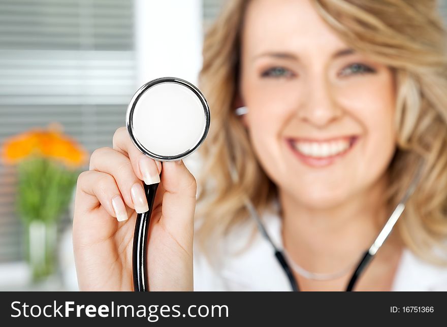 Close-up of stethoscope, being held by smiling female doctor, focus on instrument. Close-up of stethoscope, being held by smiling female doctor, focus on instrument