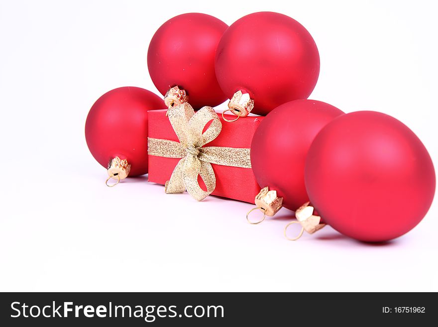 Red matte christmas balls and a gift in red wrapping on white background, with space for your text. Red matte christmas balls and a gift in red wrapping on white background, with space for your text