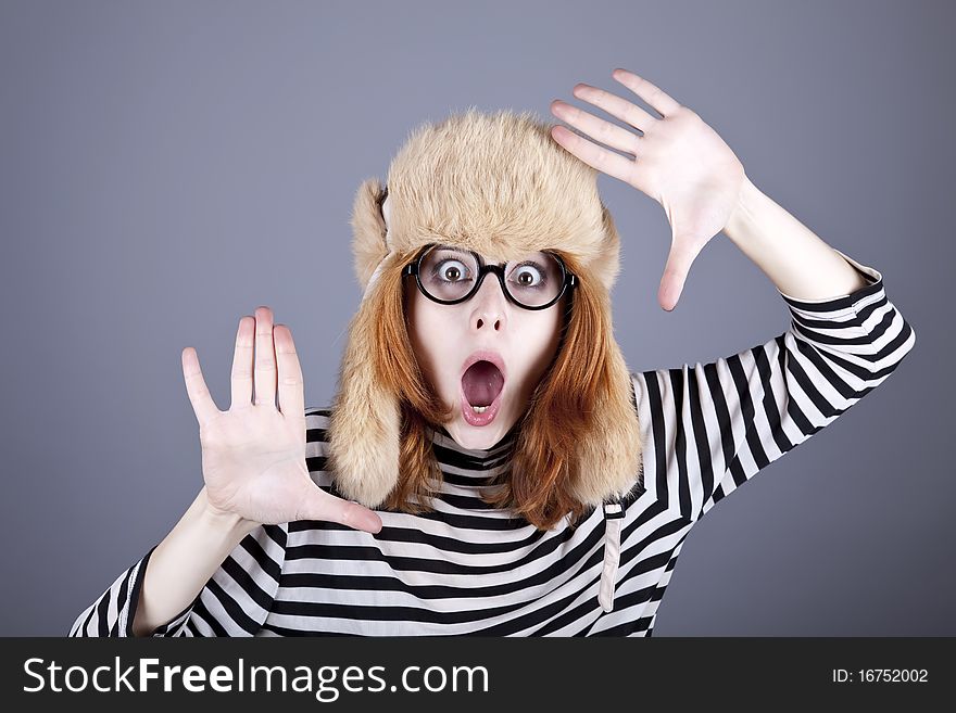 Funny girl in winter cap and glasses. Studio shot.