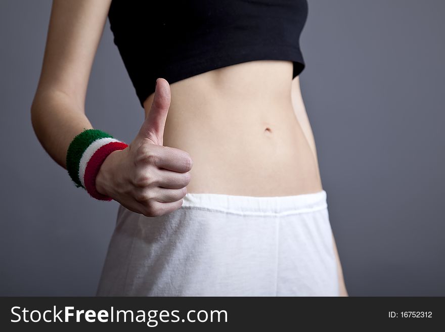 Beautiful and strong women's abs show hand OK. Studio shot.