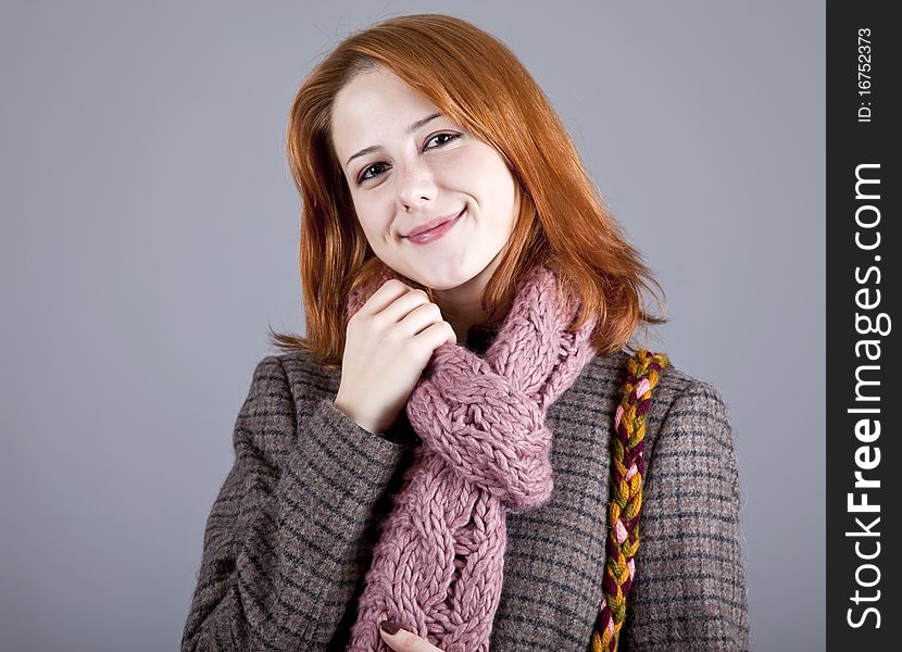 Portrait of beautiful red-haired girl in coat. Studio shot.