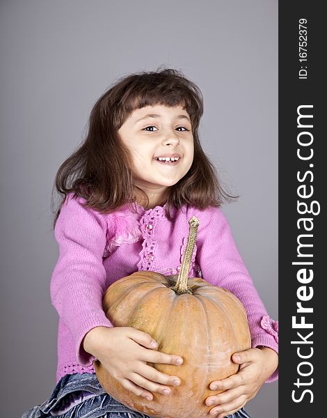 Smiling little girl with pumpkin. Studio shot.