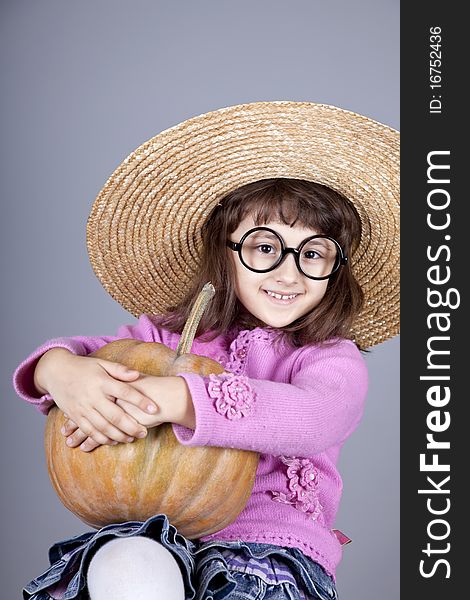 Funny girl in cap and glasses keeping pumpkin.