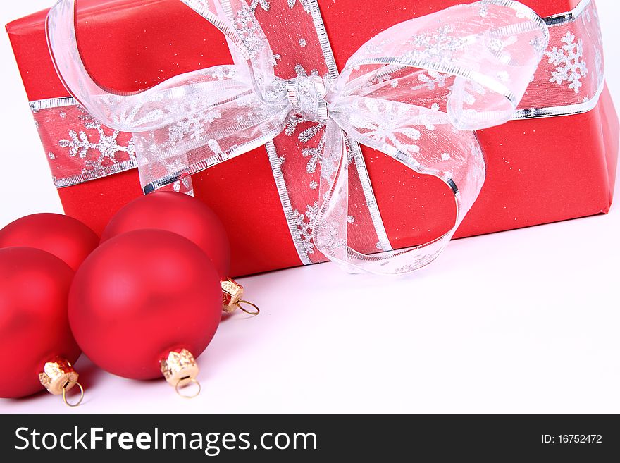 Red matt christmas balls and a gift in red wrapping on white background, with space for your text. Red matt christmas balls and a gift in red wrapping on white background, with space for your text