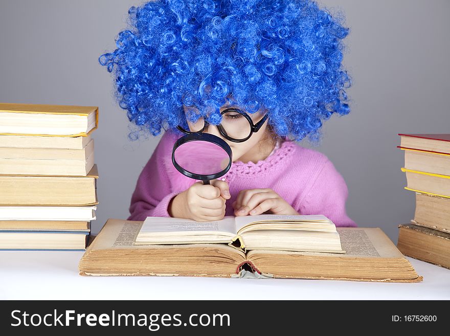 Funny blue-haired girl with loupe and books. Studio shot.