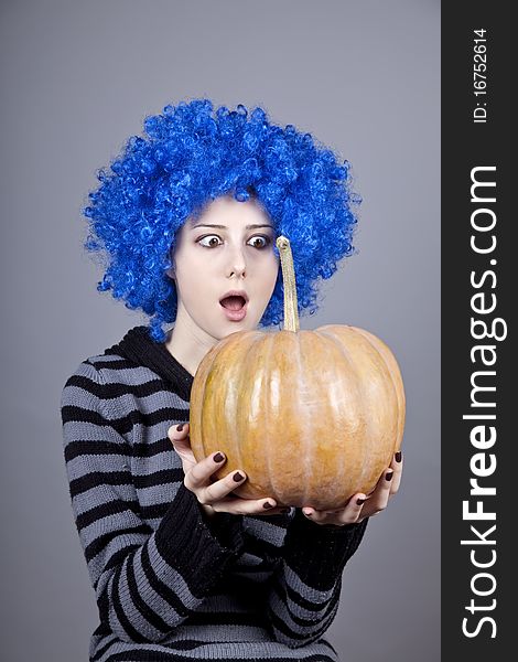 Funny girl with blue hair keeping pumpkin. Studio shot.