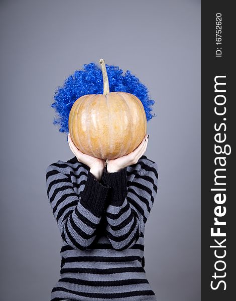 Funny girl with blue hair keeping pumpkin. Studio shot.