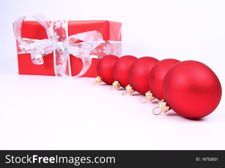 Red matt christmas balls and a gift in red wrapping on white background, with space for your text. Red matt christmas balls and a gift in red wrapping on white background, with space for your text