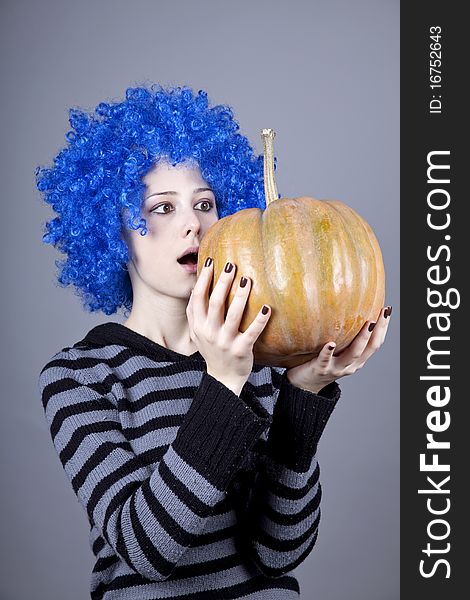 Funny girl with blue hair keeping pumpkin. Studio shot.