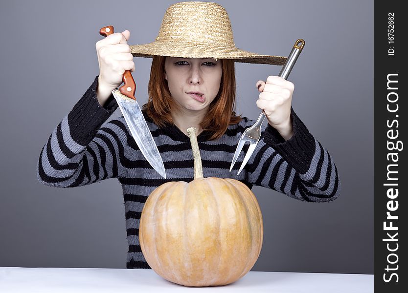 Funny girl in cap try to eat a pumpkin.