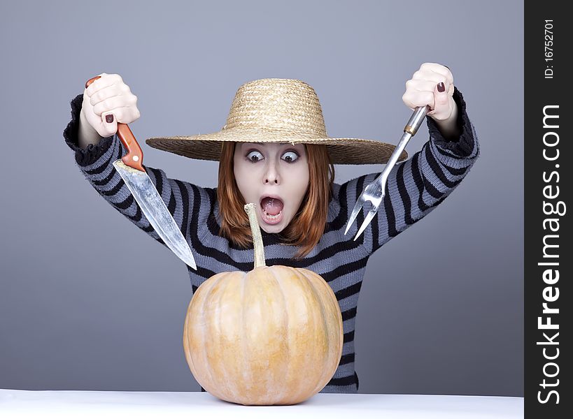 Funny girl in cap try to eat a pumpkin.