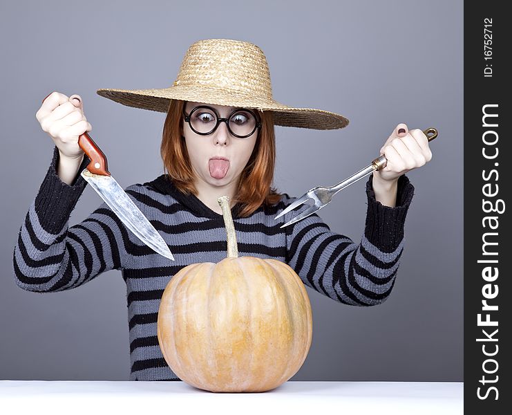 Funny girl in cap try to eat a pumpkin.