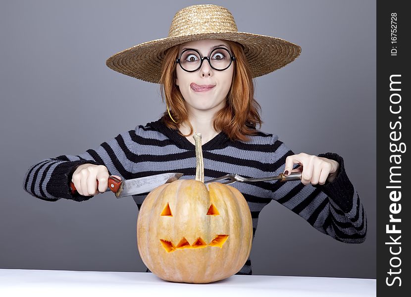 Funny girl in cap try to eat a pumpkin.