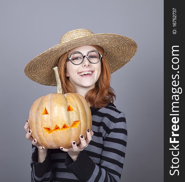 Funny girl in cap showing pumpkin. Studio shot.