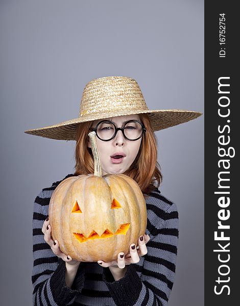 Funny girl in cap showing pumpkin.