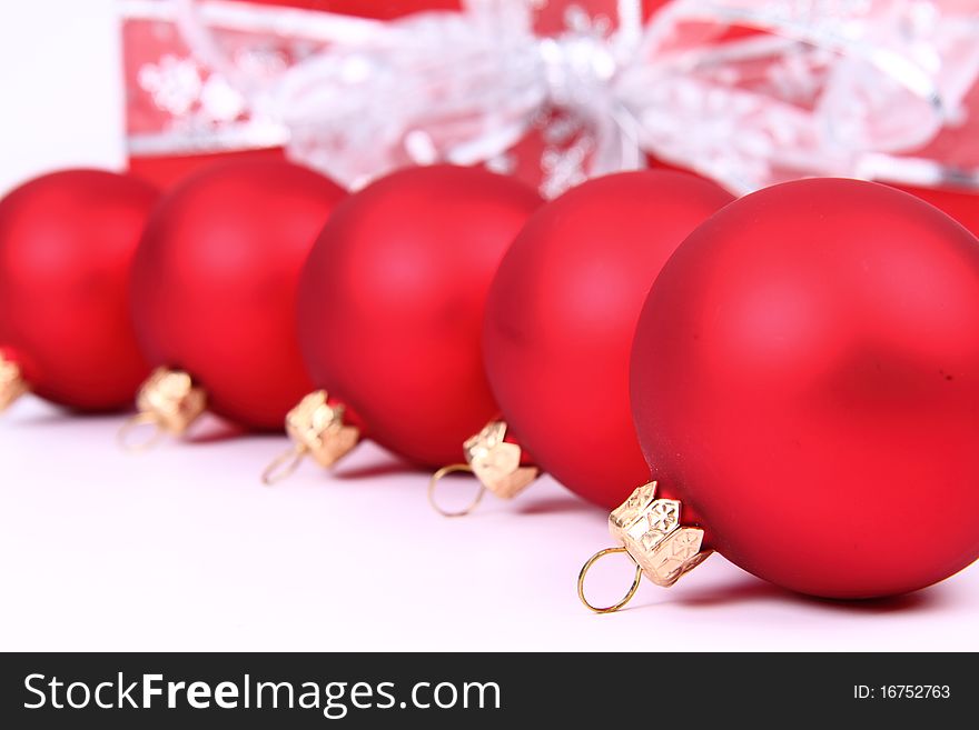 Red matt christmas balls and a gift in red wrapping on white background, with space for your text. Red matt christmas balls and a gift in red wrapping on white background, with space for your text