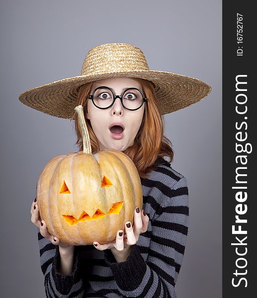 Funny girl in cap showing pumpkin. Studio shot.