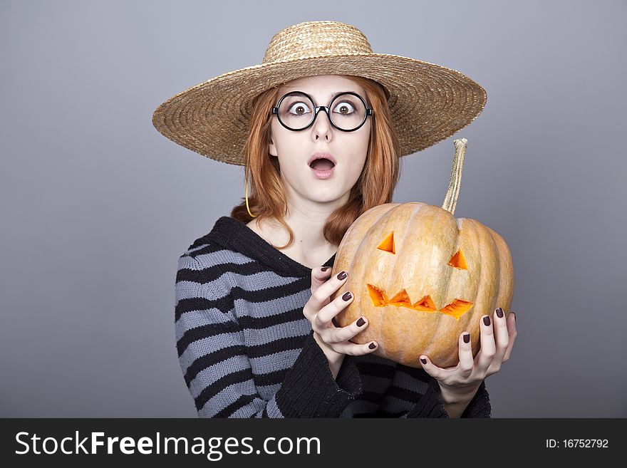 Funny girl in cap showing pumpkin. Studio shot.