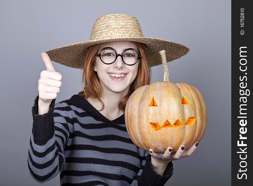 Funny girl in cap showing pumpkin. Studio shot.