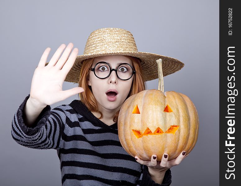 Funny girl in cap showing pumpkin. Studio shot.