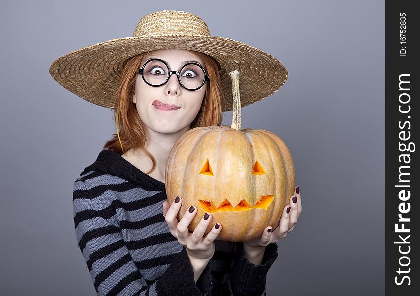 Funny girl in cap showing pumpkin. Studio shot.