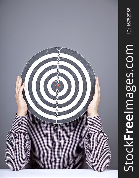 Boy with dartboard in place of head. Studio shot.