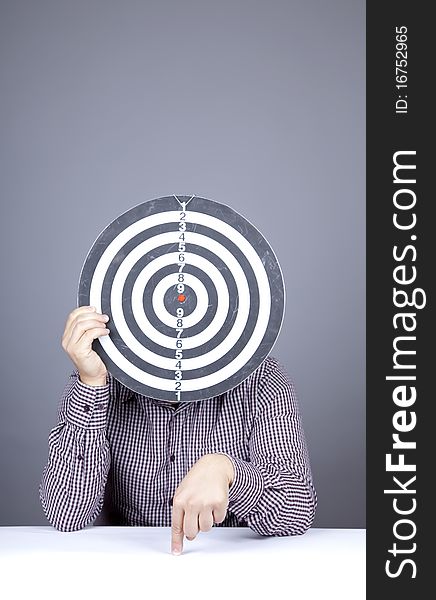 Boy with dartboard in place of head. Studio shot.