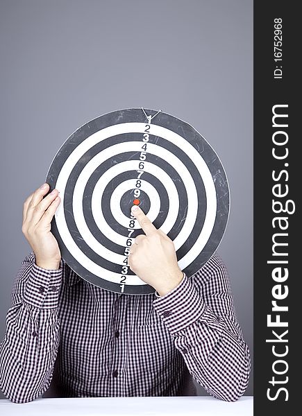 Boy with dartboard in place of head. Studio shot.