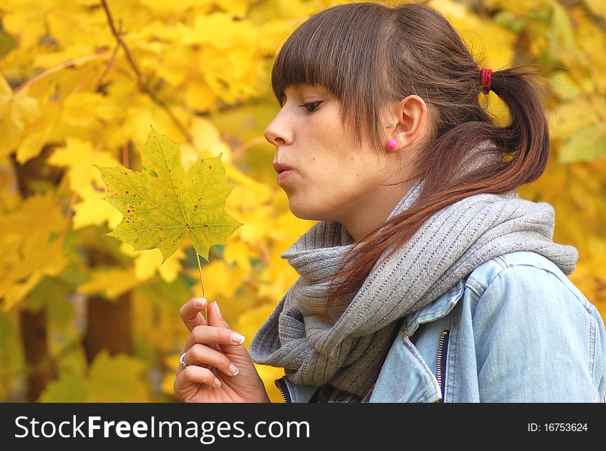 A girl holding a maple leaf in autumn scenery. A girl holding a maple leaf in autumn scenery