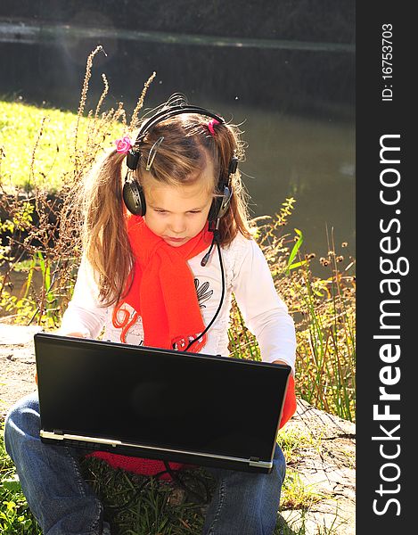 Little girl with a laptop next to the lake
