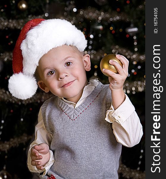 Adorable little boy wearing a Santa Hat in front of a Christmas tree. Adorable little boy wearing a Santa Hat in front of a Christmas tree