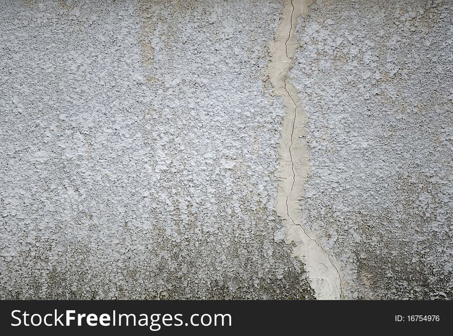 A grey concrete wall with a crack as a background. A grey concrete wall with a crack as a background
