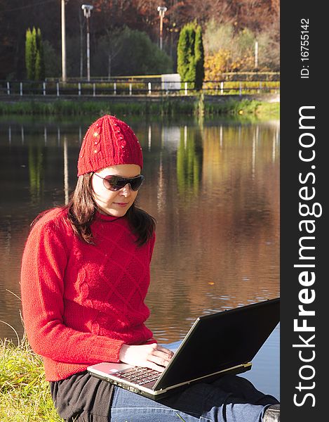 Young woman with laptop on the embankment.