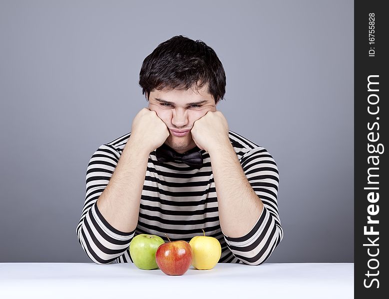 The young disappointed men with three apples. Studio shot.