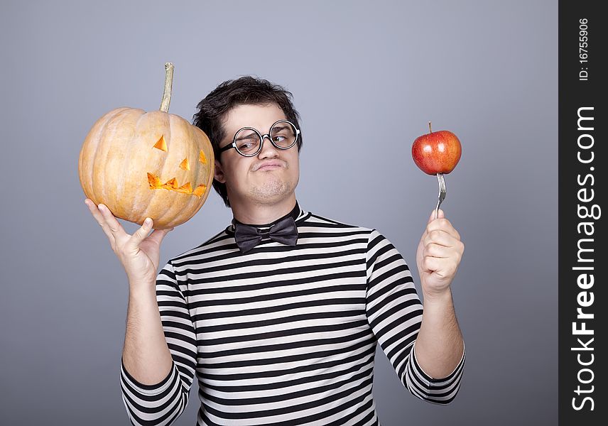 Funny men keeping pumpkin and apple. Studio shot.