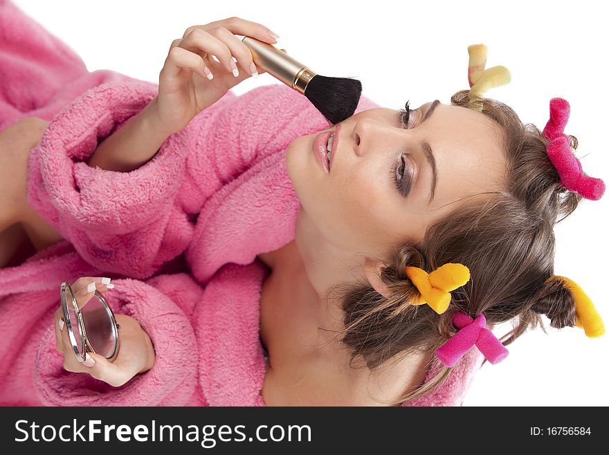 Portrait of beautiful woman in pink bath robe making-up, on white background