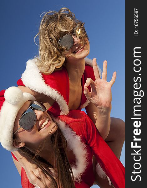 Two happy girls in Santa Clause suit having fun on the beach. Two happy girls in Santa Clause suit having fun on the beach