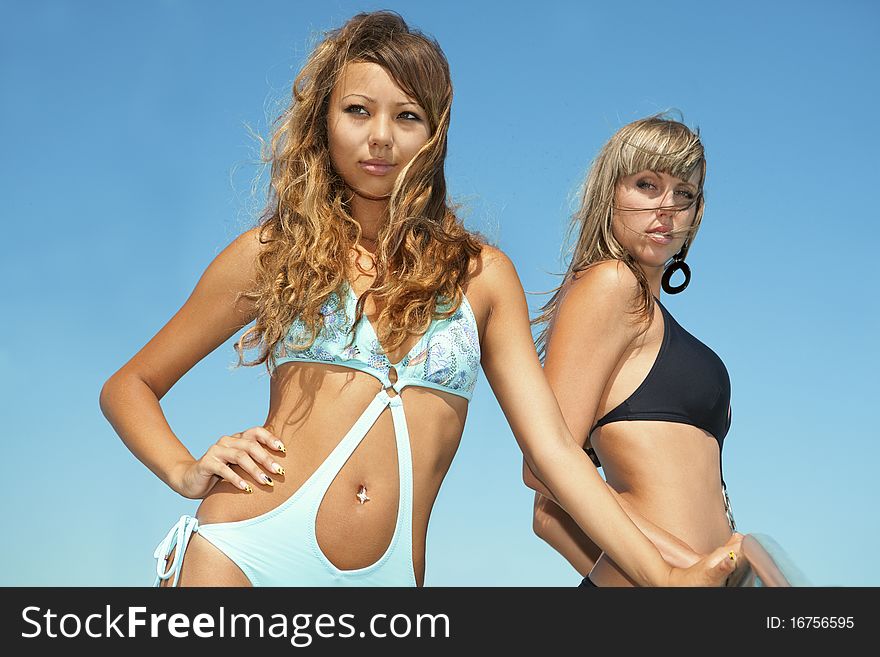 Two beautiful bikini model against blue sky