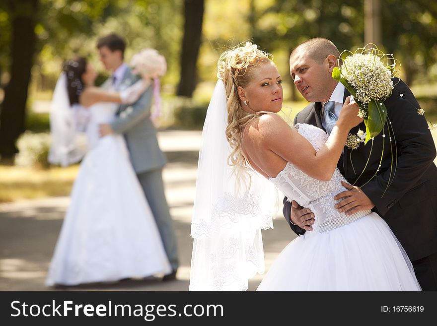 Happy bride and groom at the wedding walk embracing on the background of other newlyweds