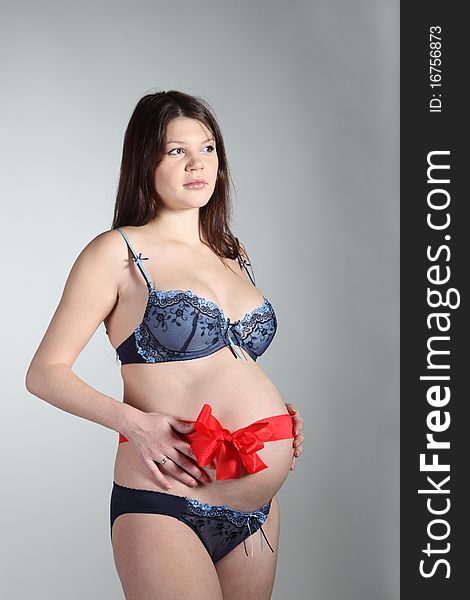 Young pregnant woman with a ribbon with a bow on her stomach