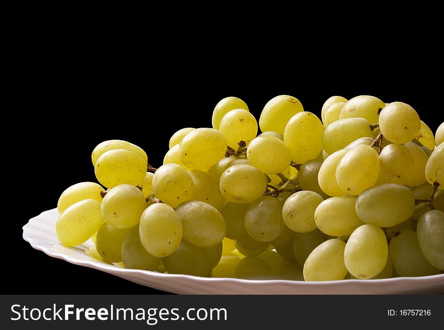 Grape bunch on the white plate fragment isolated over black background (macro shot). Grape bunch on the white plate fragment isolated over black background (macro shot)