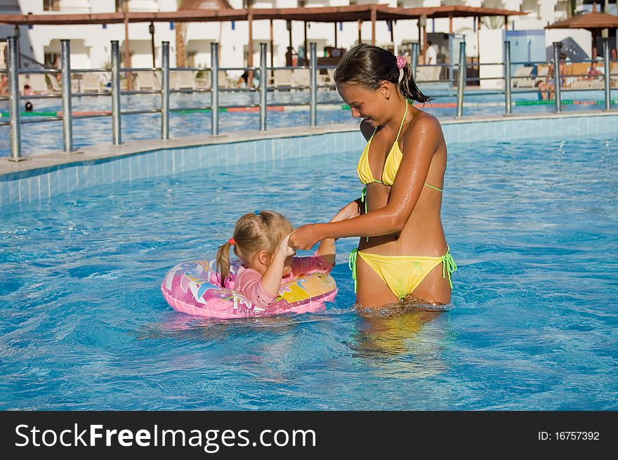 Two girls float in pool resort